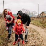 Happy family enjoying a rainy day outside with a bike ride and playful togetherness.